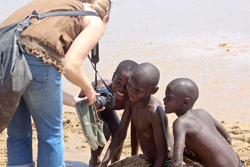 caucasian lady showing her camera to african kids