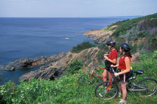 Two women looking at the sea with their mountain bike