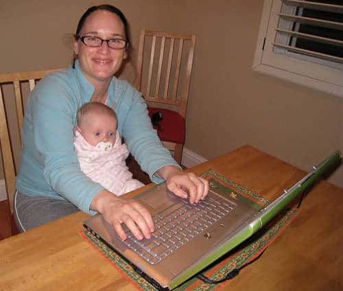 Mom with her baby on lap working on her laptop