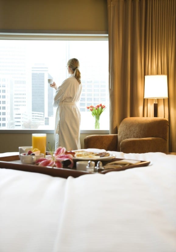 Lady in a hotel room looking at the window drinking coffee