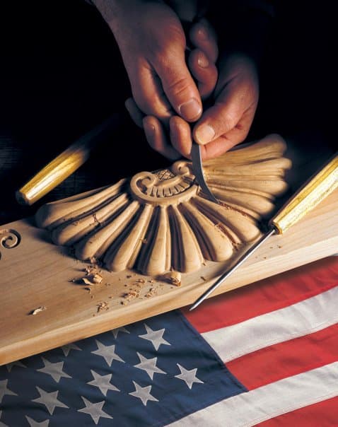 man doing woodcarving and flag of USA